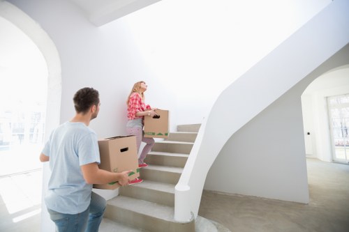Professional movers carrying furniture through a period property staircase